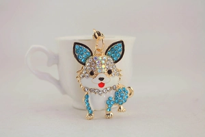 Detail eines süßen Hunde-Schlüsselanhängers mit blauen Strasssteinen an einer weißen Tasse