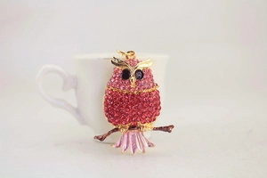 Close-up of pink rhinestone owl keychain hanging on a white coffee cup edge
