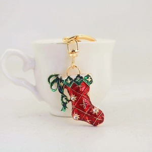 Christmas stocking keychain with red enamel and rhinestones hanging on a white cup