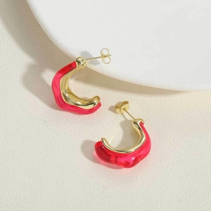 Detalle de los pendientes de resina roja en forma de C con detalles en metal dorado