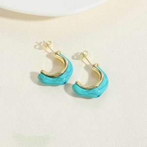 Detalle de los pendientes en C de resina con textura turquesa y acabado metálico dorado