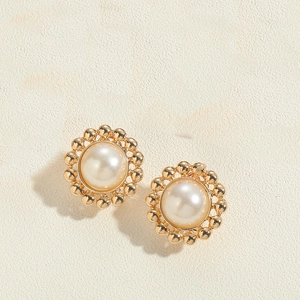 Detail of vintage style golden metal stud earrings featuring a large round pearl center