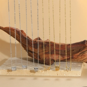 Minimalist zircon pendant necklace collection in silver and gold on a wooden stand