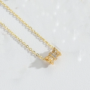 Detail of gold bow pendant necklace featuring micro-pave cubic zirconia on a leather background
