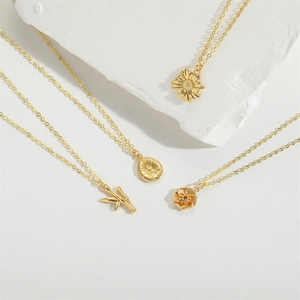 Collane vintage placcate oro con ciondolo a girasole su espositore in pietra bianca