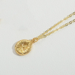 Dettaglio del ciondolo a raggiera dorata con motivi radiali su collana fine