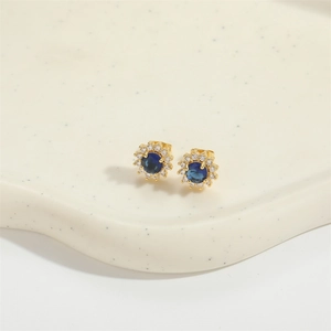 Detailed close-up of golden sunflower stud earrings with blue zircon and pavé halo