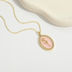 Golden necklace with pink enamel floral pendant surrounded by zircon on ceramic tray