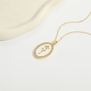 Elegant gold necklace with oval floral pendant and diamond inlay on ceramic tray