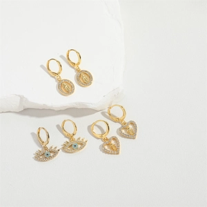 Three pairs of vintage gold hoop earrings with religious medals and evil eye charms