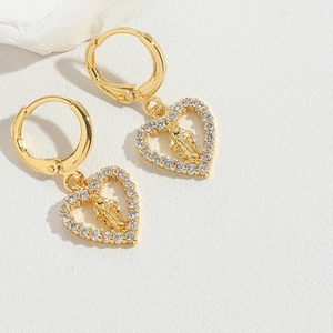 Detailed close-up of golden heart earrings featuring a religious saint relief and pavé zircons