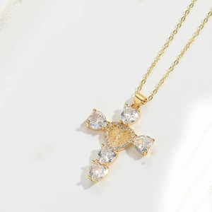 Macro detail of gold cross pendant with heart-shaped zircons and Virgin Mary relief
