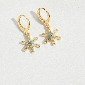 Detailed macro view of gold star hoop earrings with crystal pavé and blue eye design