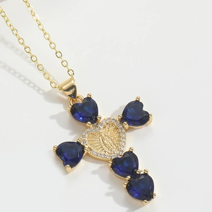 Macro shot of gold cross necklace with blue heart gems and virgin mary relief detail