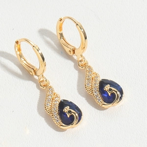 Detailed macro view of vintage gold earrings with blue gemstone and swan relief