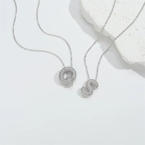 Macro detail of silver initial necklaces Q and S with shimmering zircon pavé inlay