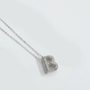 Macro view of silver letter B pendant with shimmering stones on a fine chain