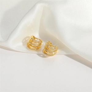 Boucles d'oreilles dorées multicouches avec zircons blancs sur fond de soie blanche