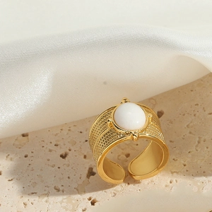 Macro view of gold plated braided ring featuring a polished white round gemstone