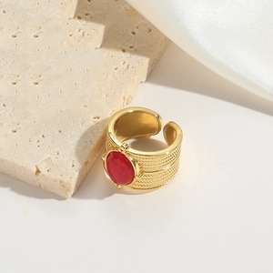 Detailed shot of gold braided ring band with red oval stone on silk fabric
