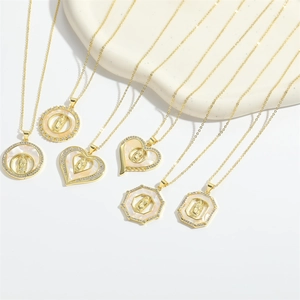 Détail de colliers dorés avec pendentifs religieux, nacre et zircons étincelants