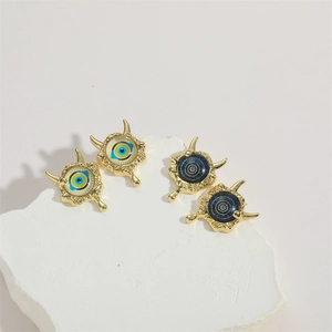 Detailed macro view of gold evil eye stud earrings on a white stone display stand