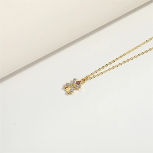 Elegant gold cross necklace with red and white zircons on a minimalist beige background