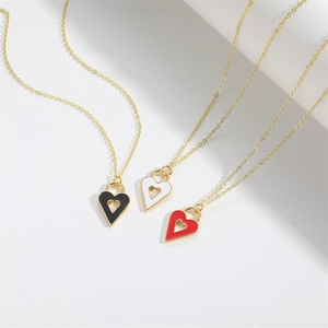 Three minimalist heart pendants in black, white and red with gold chains on white background