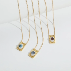 Three gold Evil Eye pendant necklaces with blue and amber stones on white background