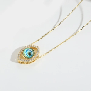 Macro shot of gold Evil Eye pendant necklace with blue center and crystal halo