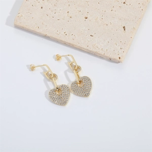 Detailed macro view of heart-shaped gold drop earrings with white pavé cubic zirconia