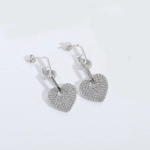 Close-up of silver heart dangle earrings featuring pave-set crystals and geometric link