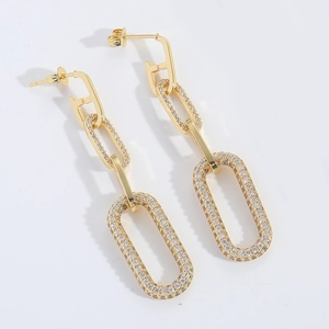 Macro shot of gold long drop earrings featuring crystal-encrusted geometric F links