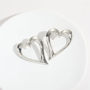 Close-up of minimalist silver hollow heart earrings on white stone display base