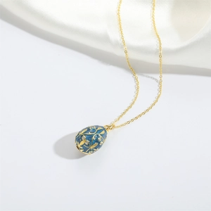 Detailed close-up of retro blue enamel egg pendant with gold floral relief and rhinestones