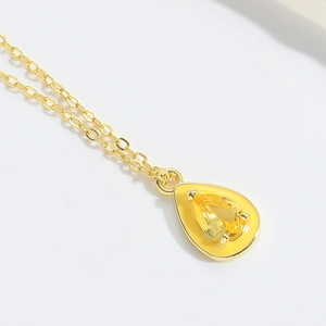 Vue macro d'un collier goutte d'eau avec émail jaune et pierre précieuse facettée