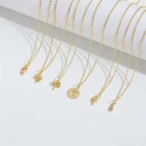 Minimalist gold necklaces with zircon tree and plant pendants on white display