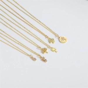Minimalist gold necklaces with cubic zirconia tree and pineapple pendants on white background
