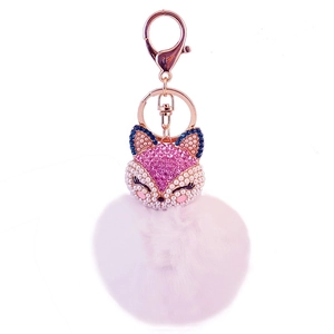 Macro shot of fox pendant with pink rhinestones, faux pearls and fluffy pompom keychain