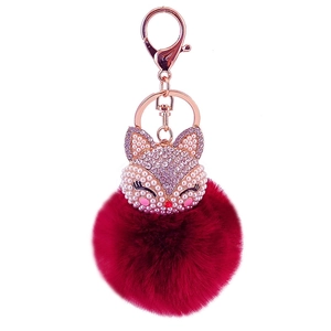 Macro shot of a fox head keychain with red faux fur ball and rose gold crystal details