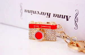Detailed shot of camera keychain with sparkling rhinestones and red enamel finish