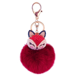 Detailed view of fox head charm with sparkling crystals and a burgundy plush pompom