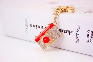 Close-up of red enamel and crystal camera keychain with a gold lobster clasp