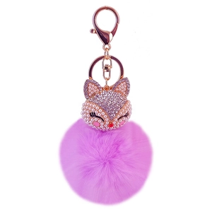 Close-up of purple faux fur ball keychain with rhinestone fox and rose gold hardware