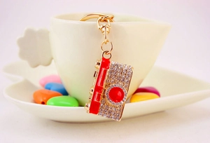 Detailed view of a crystal camera keychain featuring red enamel and gold-plated metal