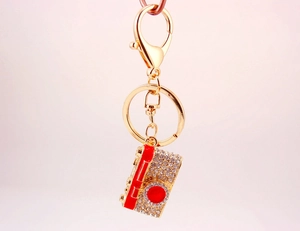 Detail view of a creative camera keychain with red enamel and shimmering rhinestones