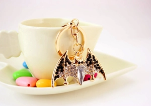 Sparkling bat keychain with rhinestones hanging on a coffee cup in a creative setting