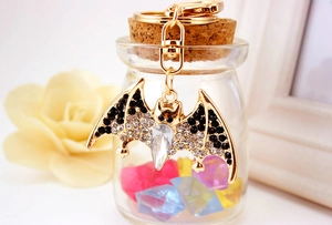 Detailed view of a bat keychain with crystals hanging on a decorative glass bottle