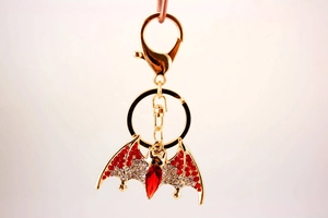 Close-up of golden bat keychain with sparkling red and white rhinestone embellishments
