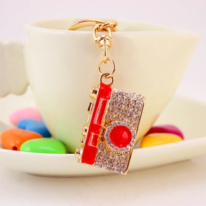 Creative rhinestone camera keychain with gold finish and red enamel details on a cup